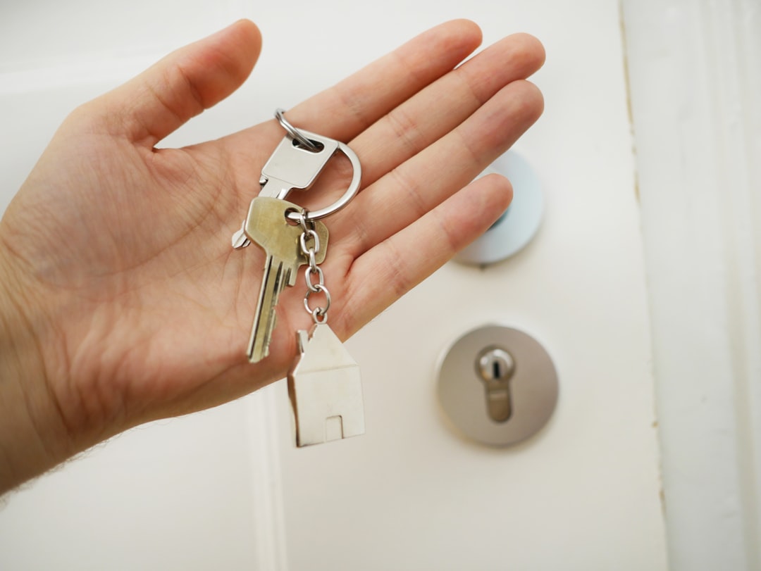 A hand holding house keys in front of a door lock
